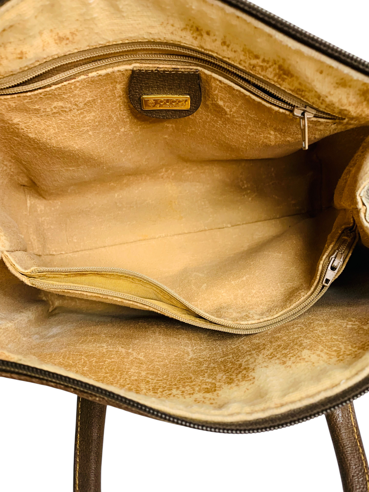Interior of a vintage Gucci handbag from Cherry's Luxury Collection featuring beige leather lining and gold logo tag.