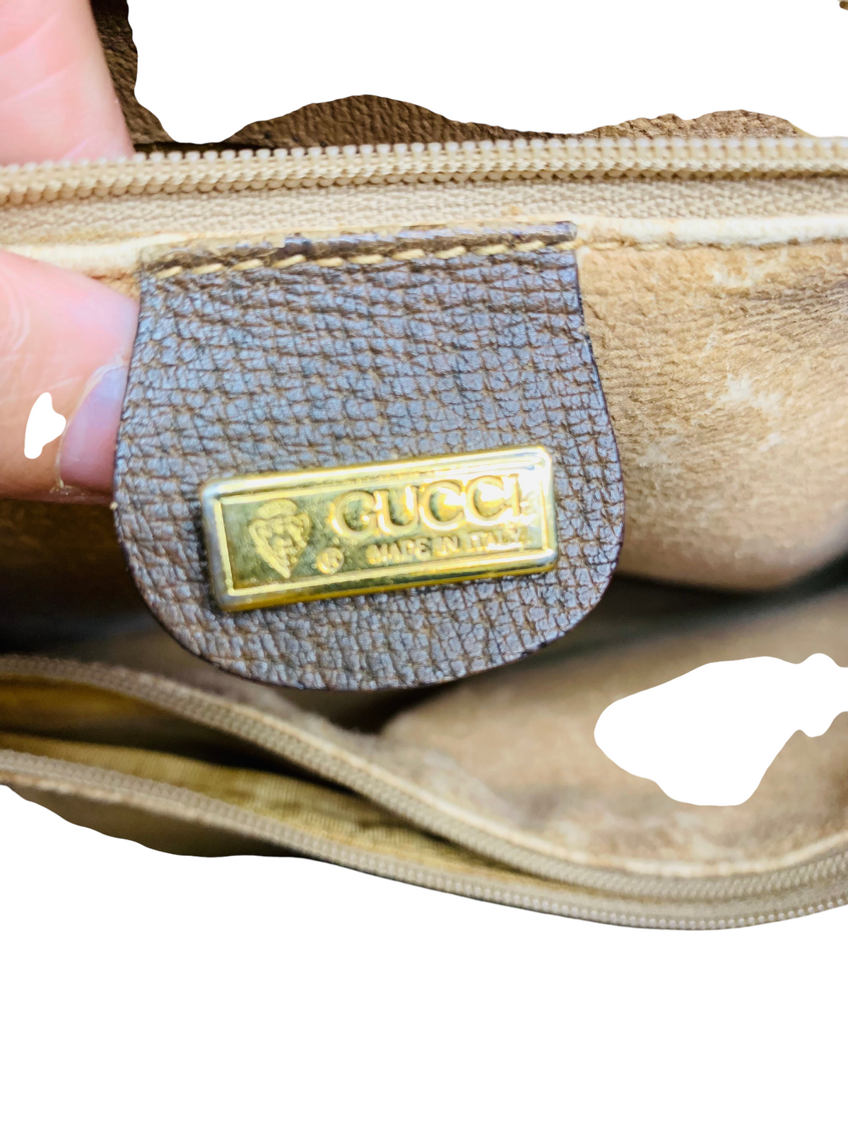 Cherry's Luxury Collection vintage Gucci handbag interior featuring a gold-tone metal logo plaque on brown leather.