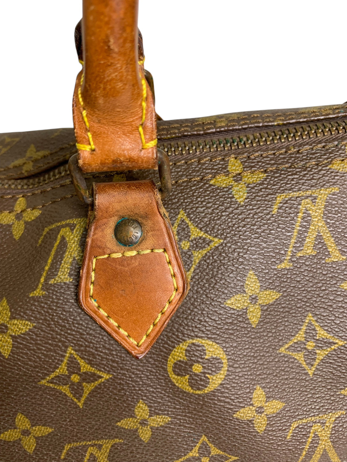 Close-up of a brown monogram coated canvas travel duffel bag with tan leather handle attachment and brass hardware.