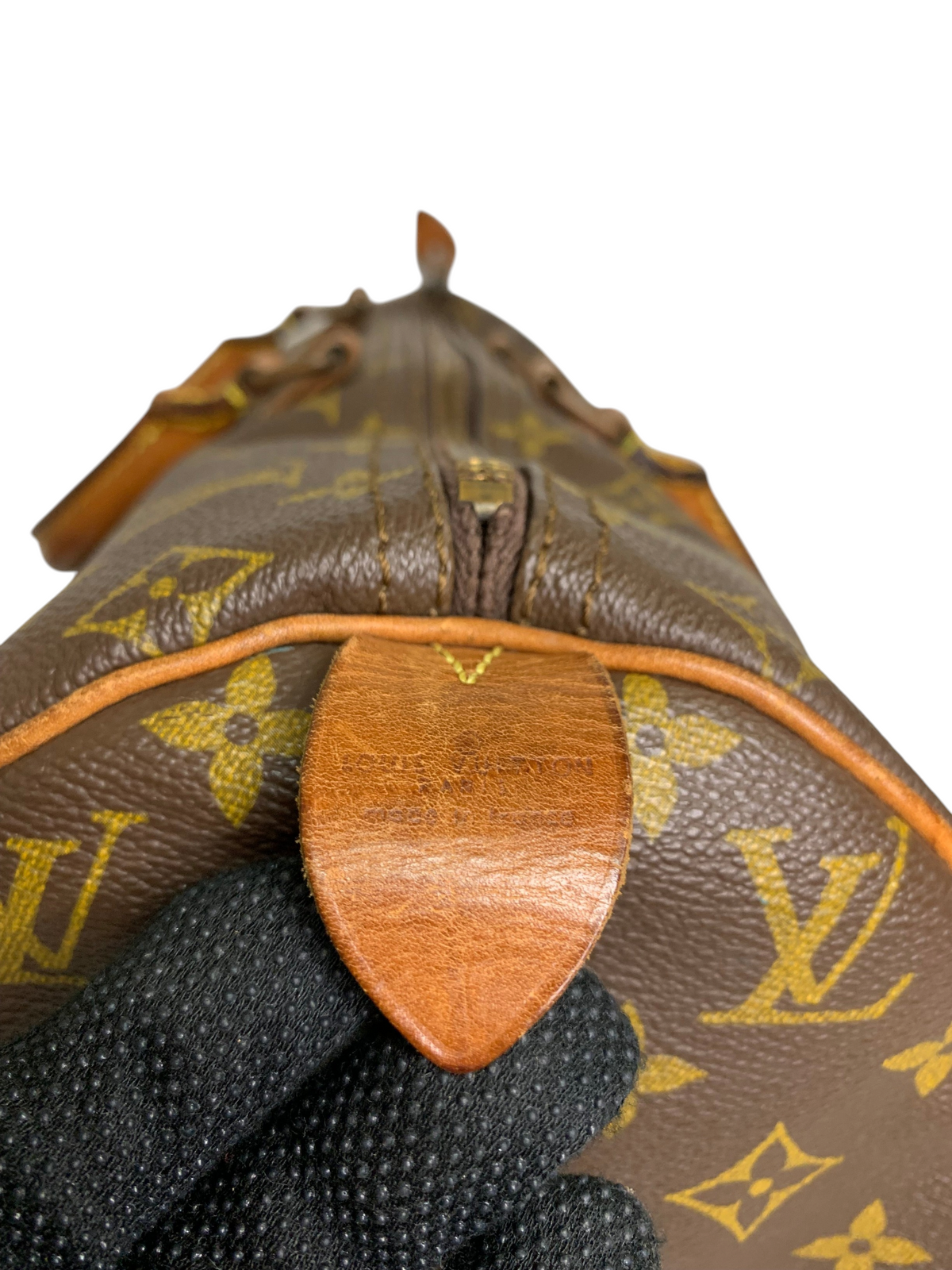 Close-up of Louis Vuitton monogram coated canvas travel duffel bag showing leather trim and embossed brand detail.