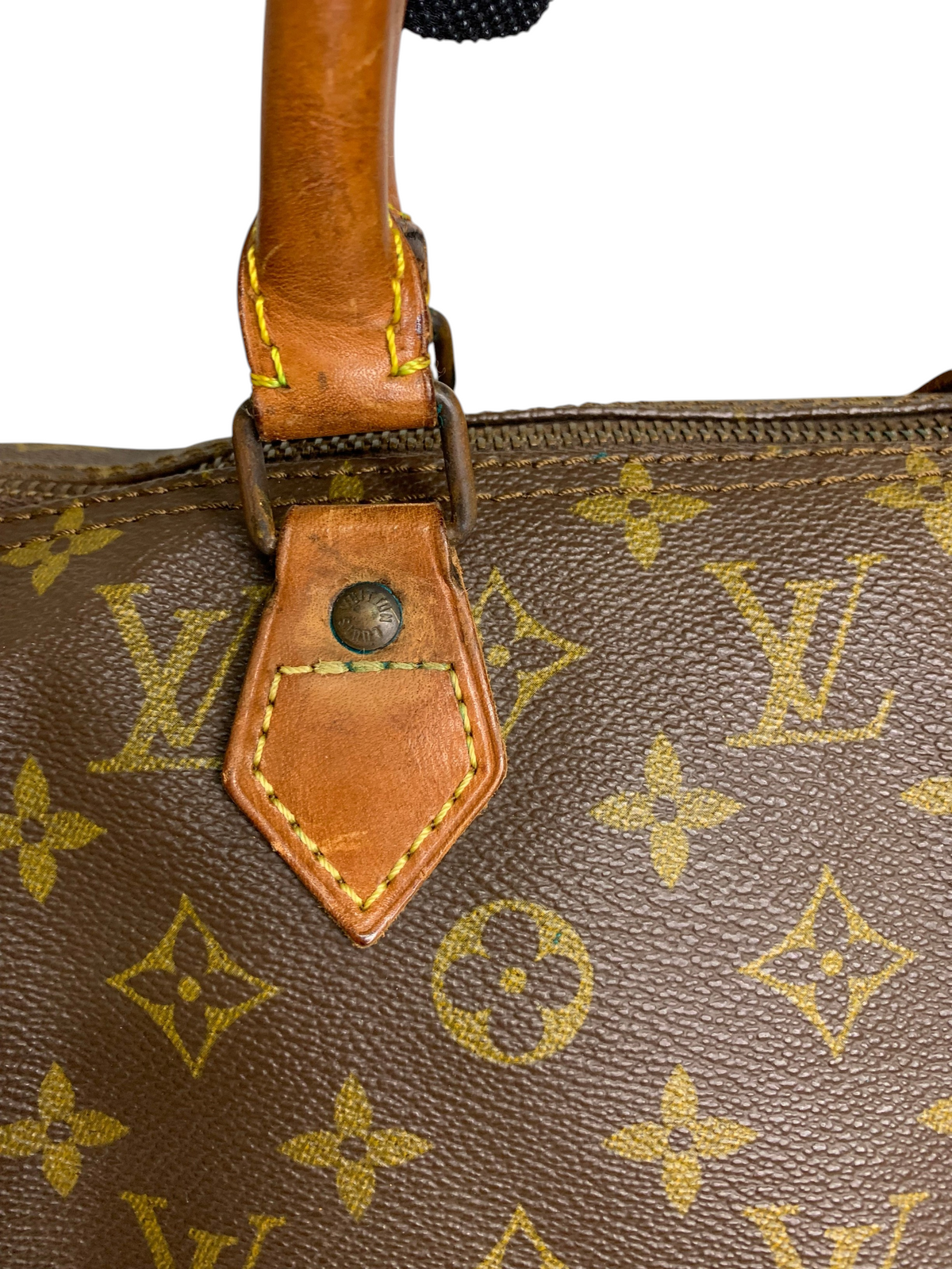 Close-up of a brown monogram coated canvas travel duffel bag with tan leather handle attachment and brass hardware.