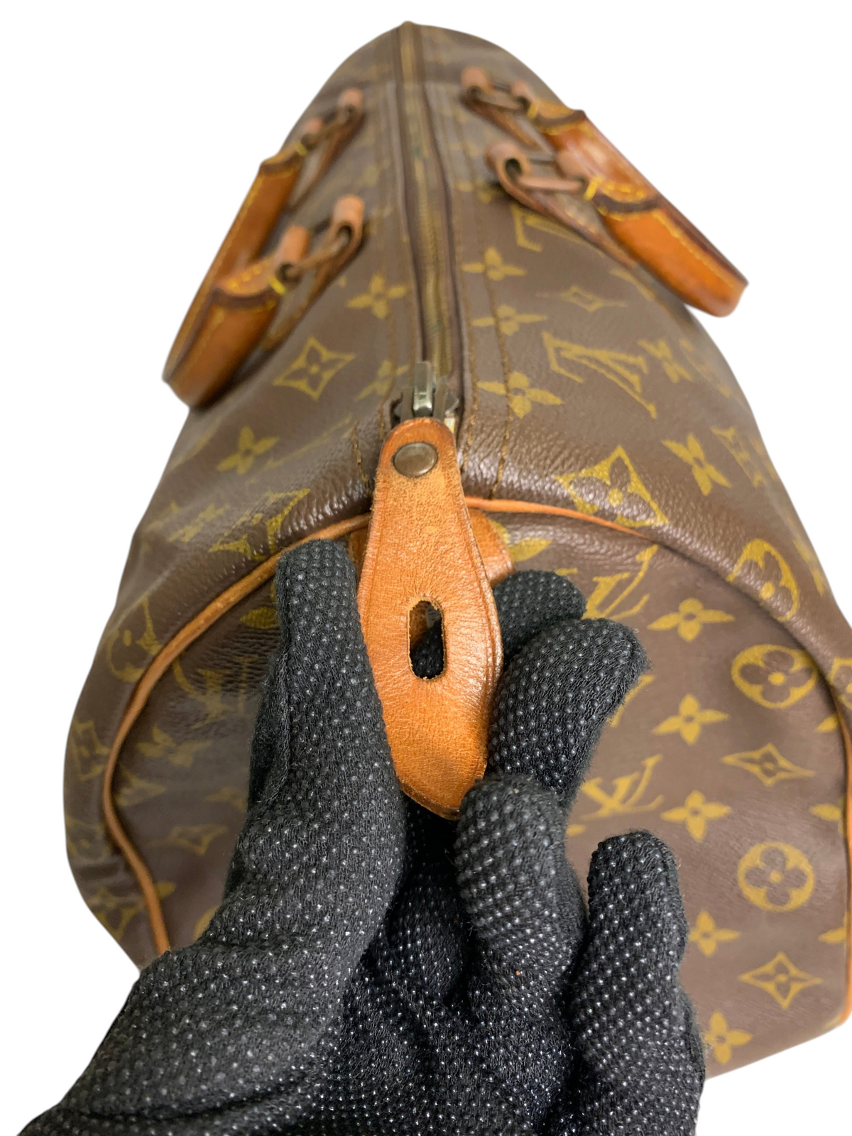 Close-up of a brown monogram canvas travel duffel bag with leather trim and a secure top-zip closure.